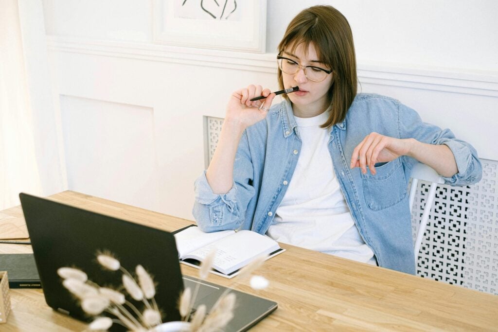 Woman looking at her notebook while her laptop is in front of her