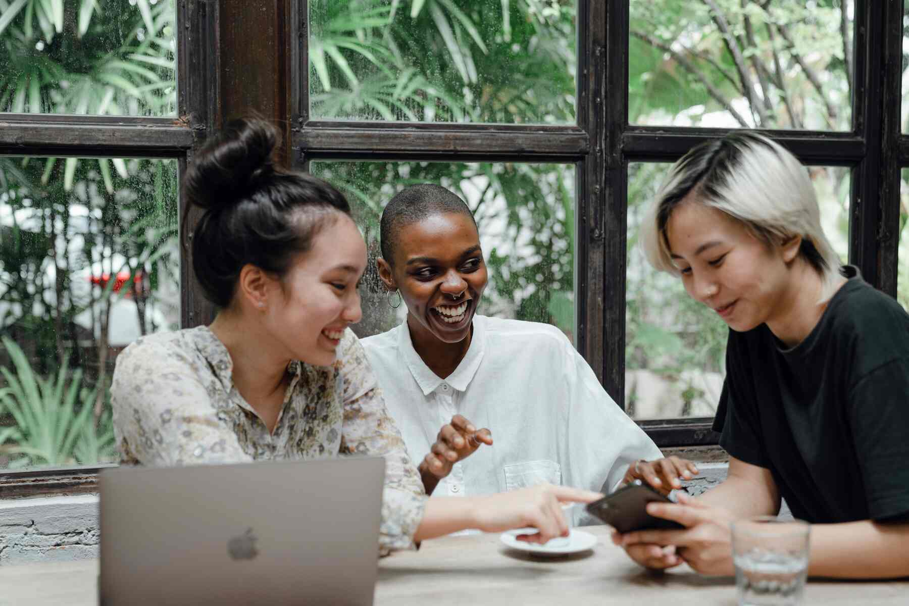 Three women smiling while looking at the phone