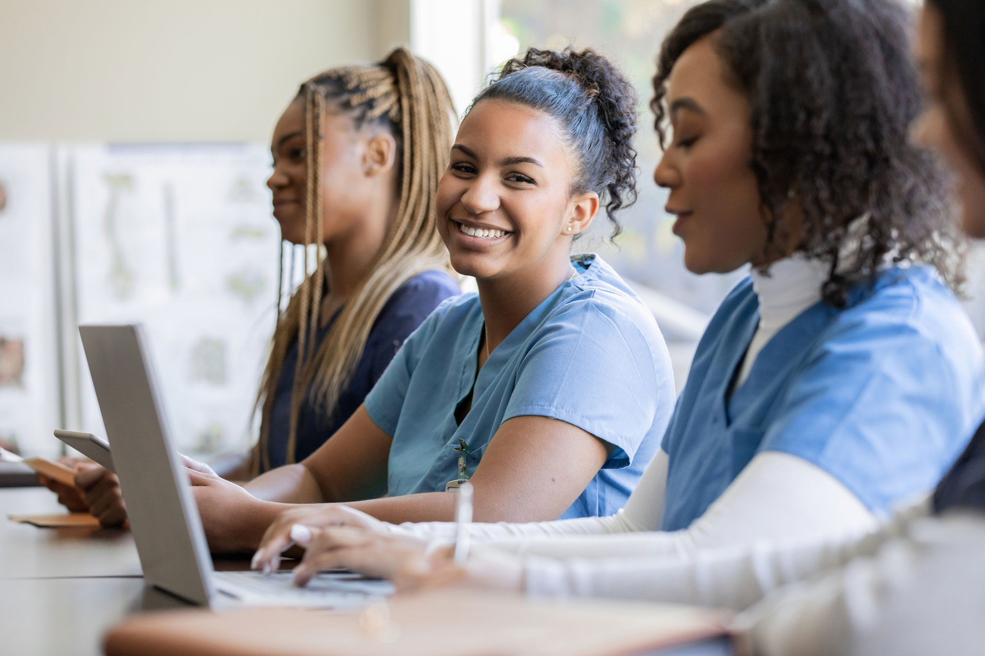 Young nurse or medical intern uses laptop computer with classmate during university training class.