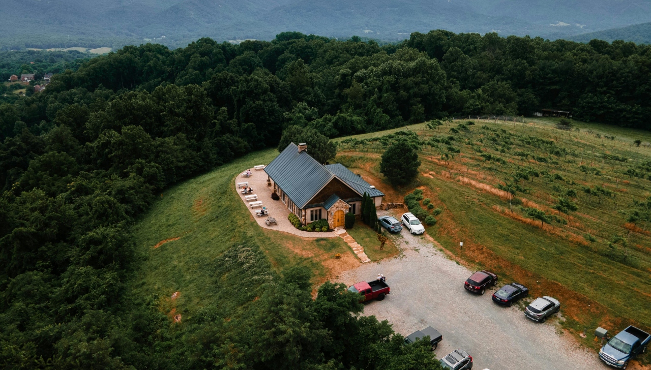 drone shot of a church in a field surrounded by woods