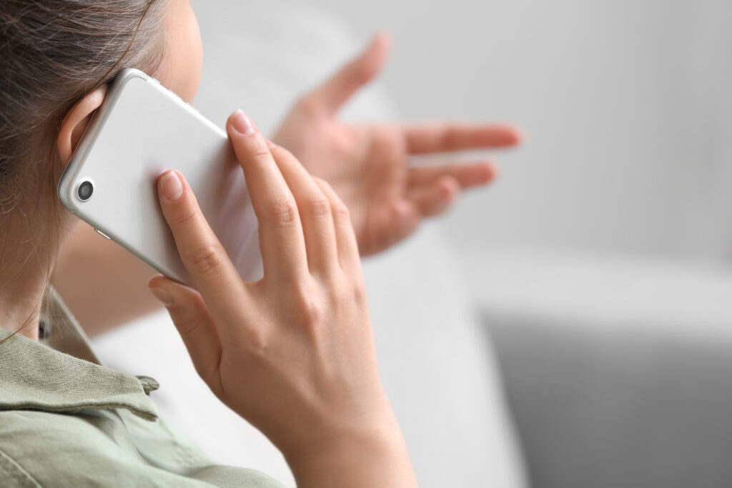 Close-up of a woman talking on a smartphone and gesturing with her hand during a phone conversation.